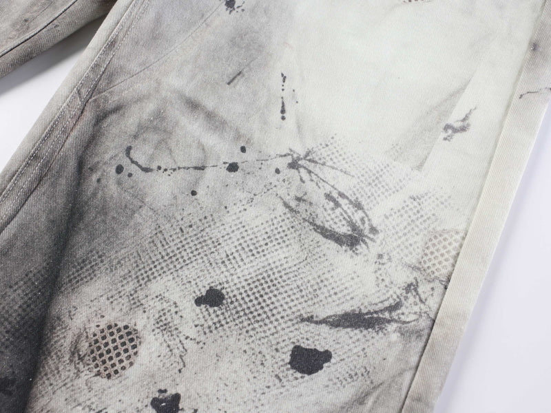 Close-up of light-wash denim leg with scattered black abstract print and textured twill