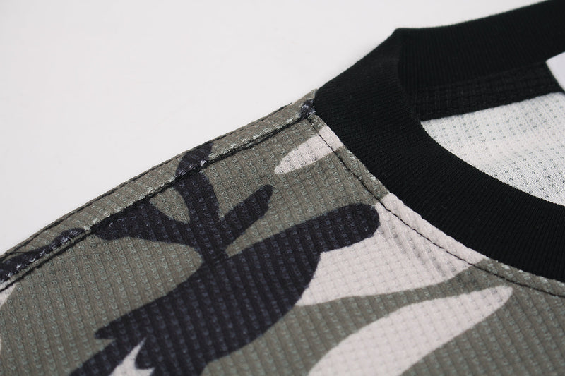 Close-up of shoulder seam on camo waffle long sleeve top with black neckline trim