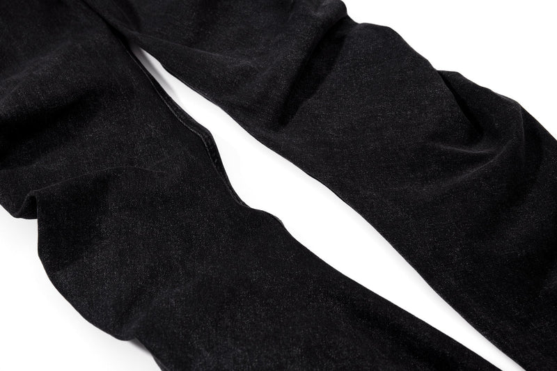 Black flare jeans leg close-up showing smooth denim and taper at the knee