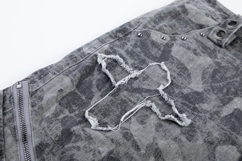 Close-up of gray distressed camo pants with frayed patch and side zipper