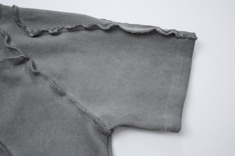 Close-up of a gray ribbed compression tee with raw seams and deconstructed distressed edges on a white background