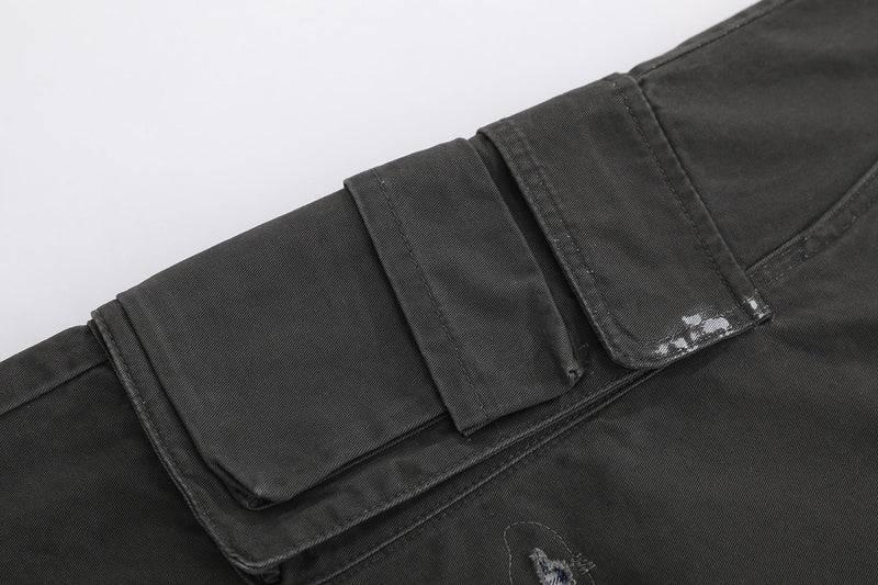 Black cargo shorts side pocket close-up with flap and distressed white marks