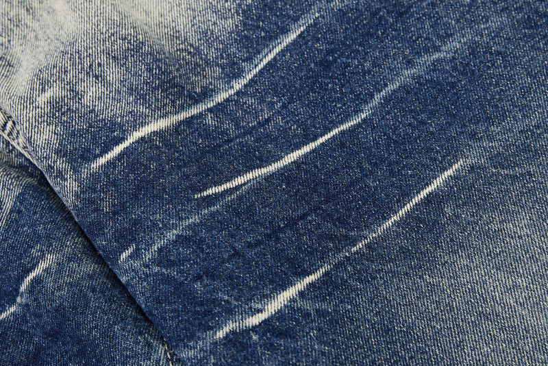 Close-up of distressed denim with diagonal faded streaks across blue fabric