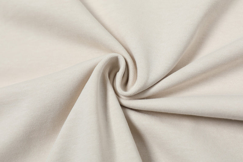 Cream textured knit fabric with soft draped folds, showcasing the minimalist Seakoff deconstructed collar tee material