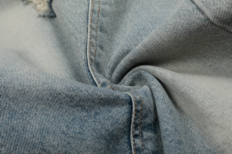 Close-up of denim shorts seam and folded leg in light bleached blue wash