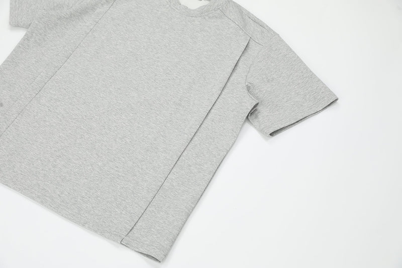 Light gray oversized structured tee with short sleeves and minimalist seam detailing on a clean white background