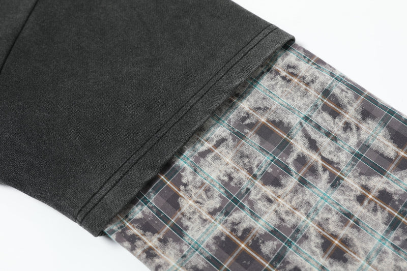 Close-up of cuff detail showing black body fabric layered over plaid sleeve fabric