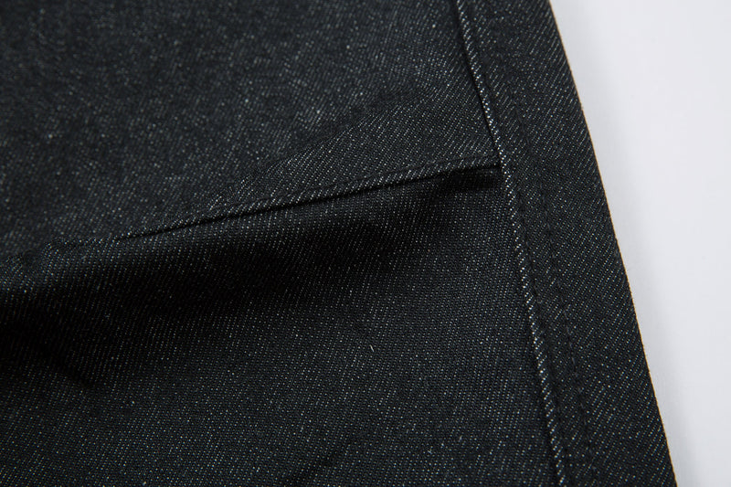 Close-up of a lower pant leg hem with dark denim stitching and folded edge