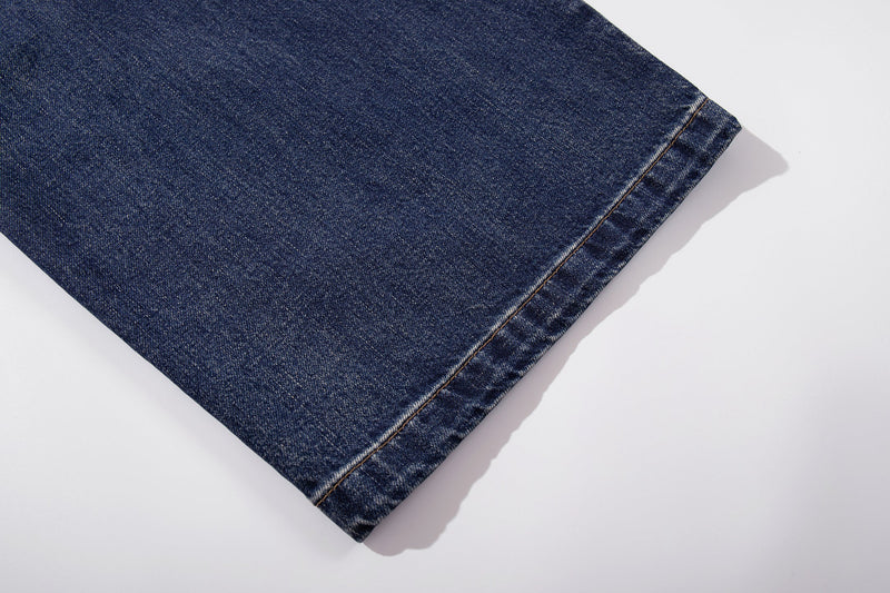 Close-up of wide hem on mid-blue washed denim jeans