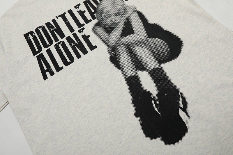 Oversized light gray graphic tee with black distressed Dont Leave Me Alone print and seated doll illustration