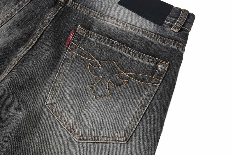 Close-up of back right pocket on faded black jeans with stitched motif and red label