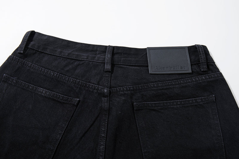 Close-up of the back waistband on black denim jeans with a black leather brand patch