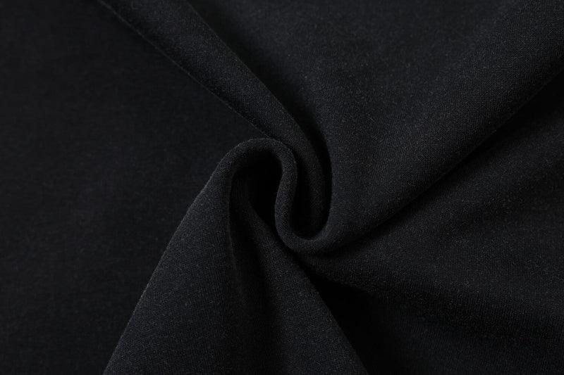 Close-up of black distressed tee fabric with soft knit texture and folded drape for a rock streetwear look