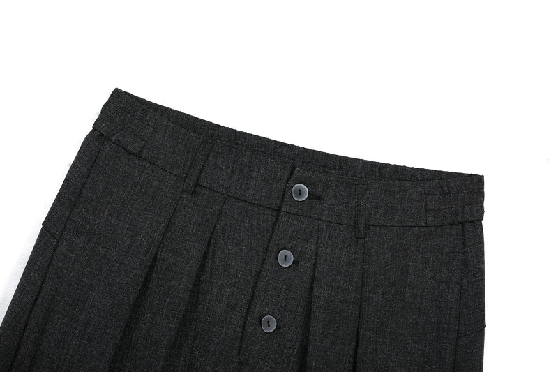 Close-up of black pants upper front with button closure and waistband