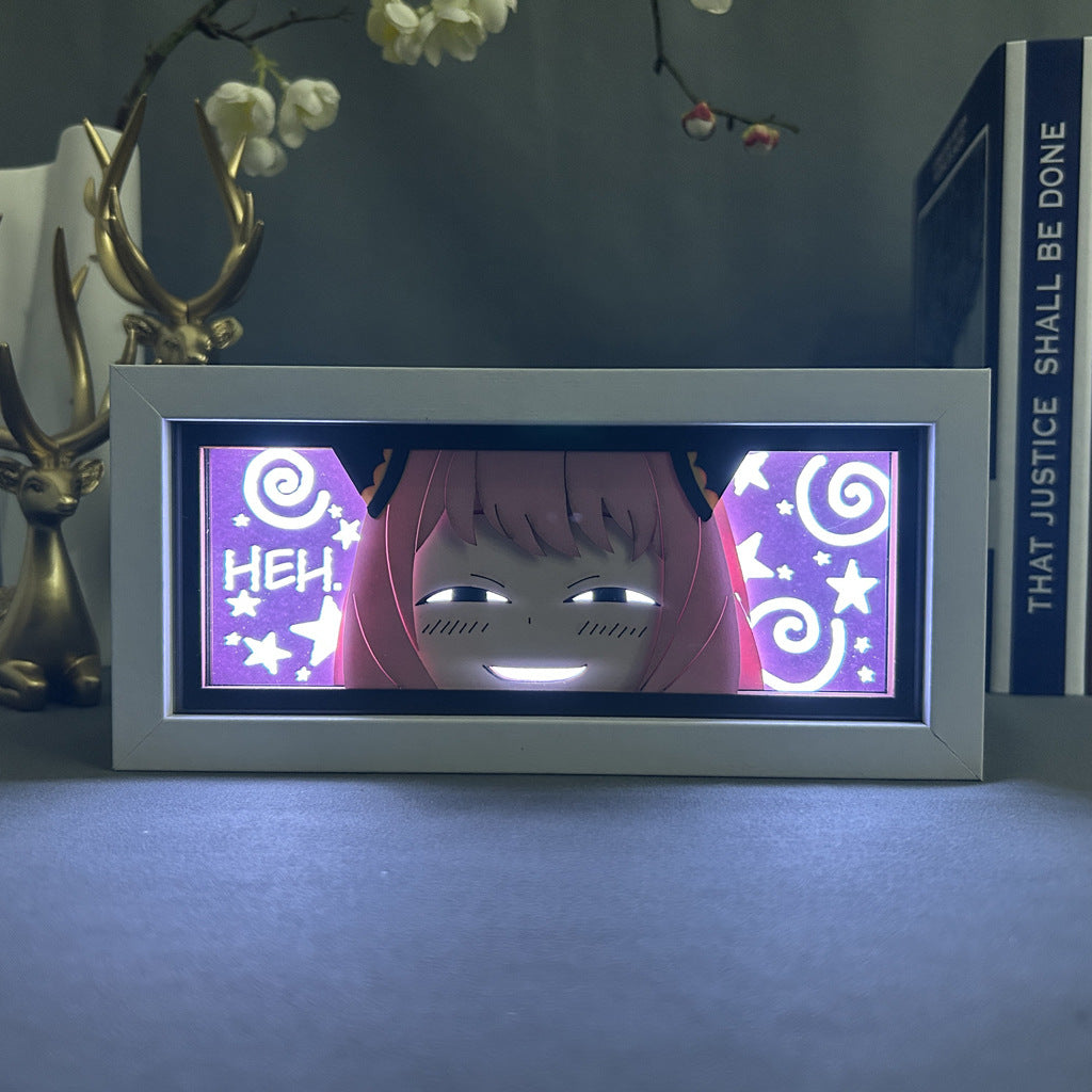 The Anime Light Box – Anya Forger 3D LED Lamp from Spy × Family showcases an anime-style face with pink hair, a grin, and dynamic color-changing effects against a starry purple backdrop. A book titled &quot;THAT JUSTICE SHALL BE DONE&quot; and a deer figure complete the scene marked by intrigue and the word &quot;HEH!.