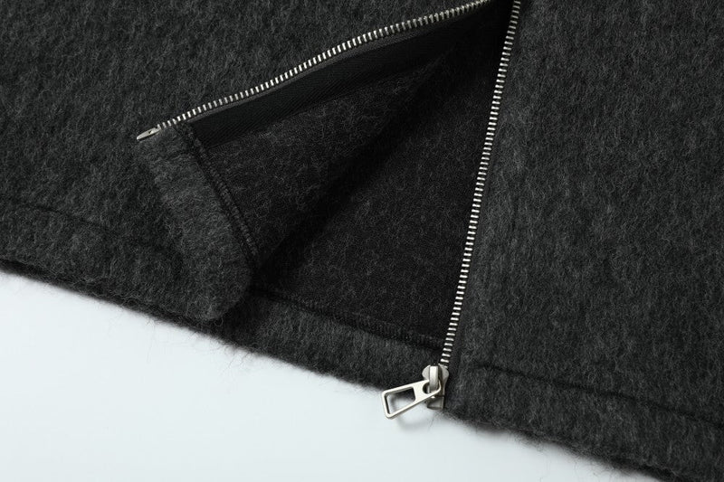 Close-up of the front zipper and lower hem on the dark wool-blend hooded jacket