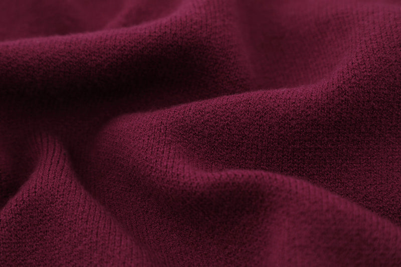 Close-up of burgundy knit sweater fabric folds and soft textured weave