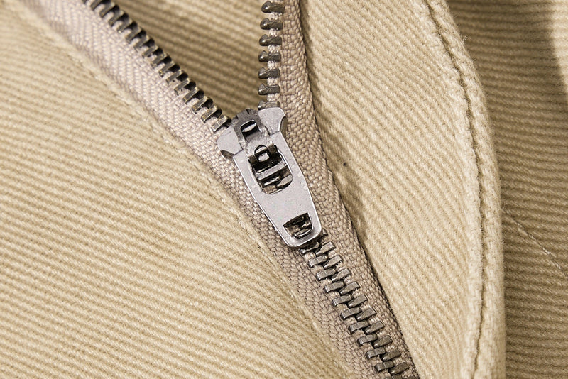 Close-up of khaki pants zipper closure with silver zipper pull