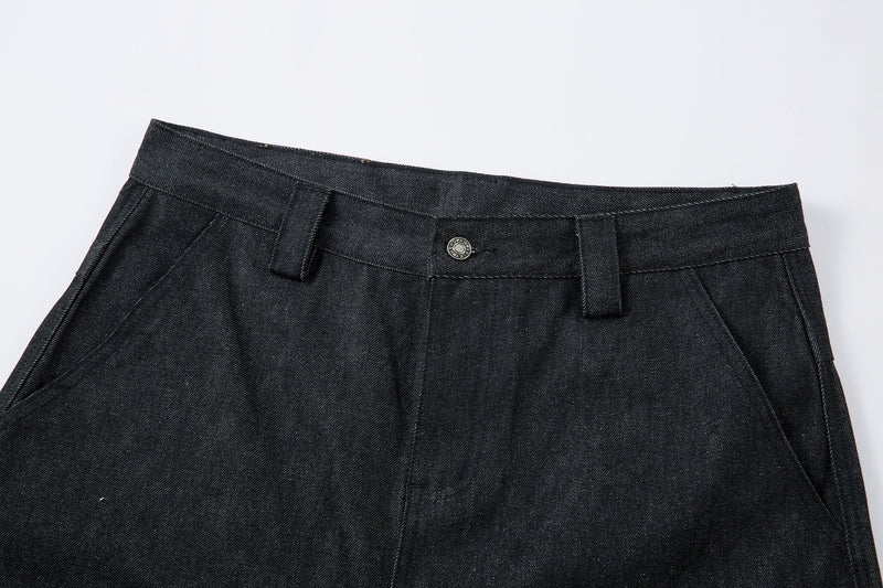 Close-up of the front waistband on dark denim pants with button closure and belt loops