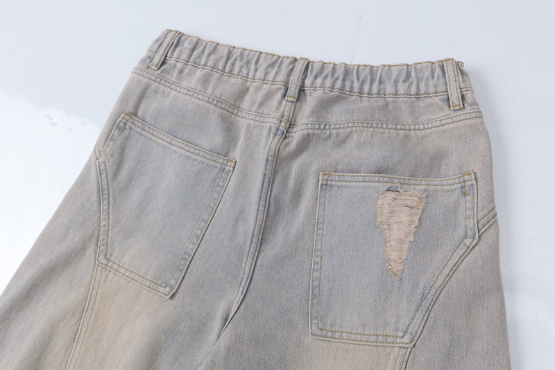 Close-up of back waistband on light wash jeans with patch pockets and distressed tear