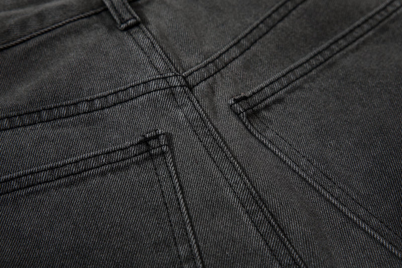 Close-up of curved seam stitching on black denim cargo pants