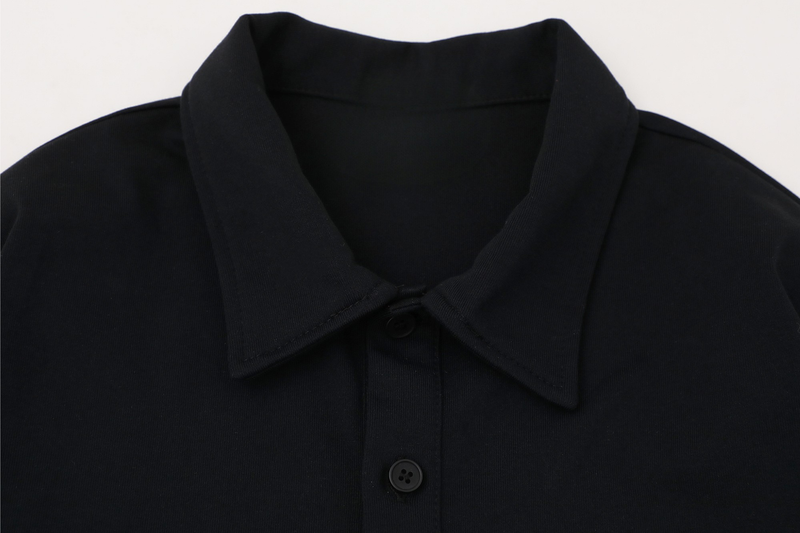 Close-up of black polo collar and button placket with matte fabric texture