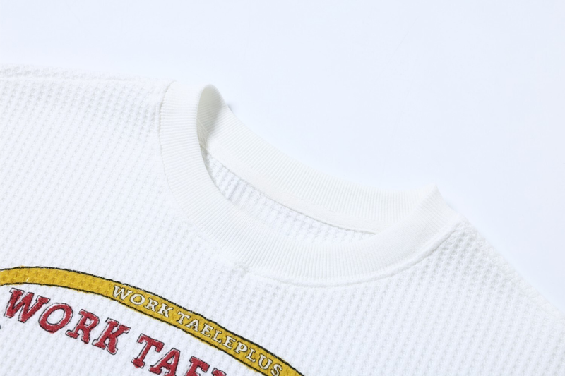 Close-up of white ribbed crew neck and waffle knit fabric texture
