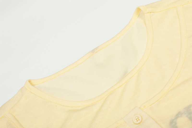 Close-up of light yellow tee neckline and shoulder seam with soft knit texture