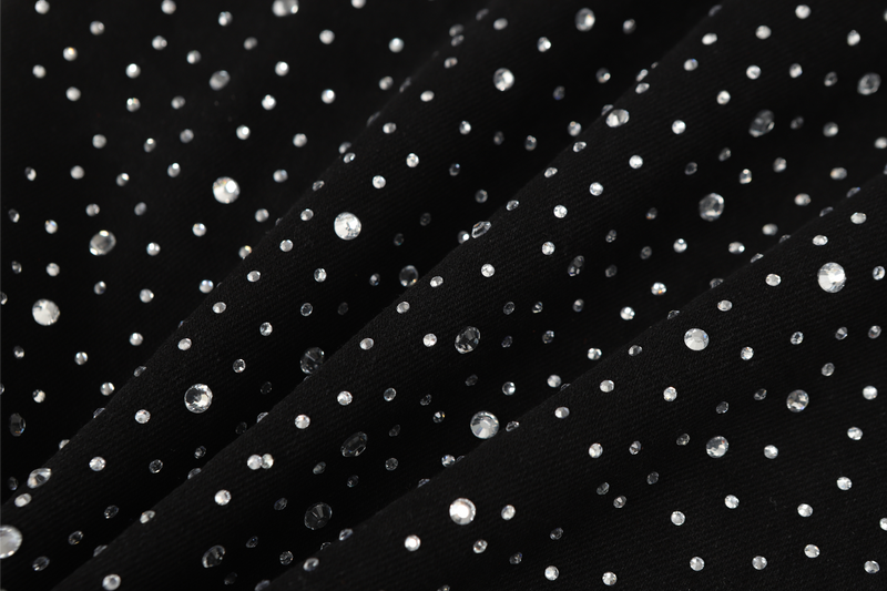Close-up of black denim fabric with scattered clear rhinestones