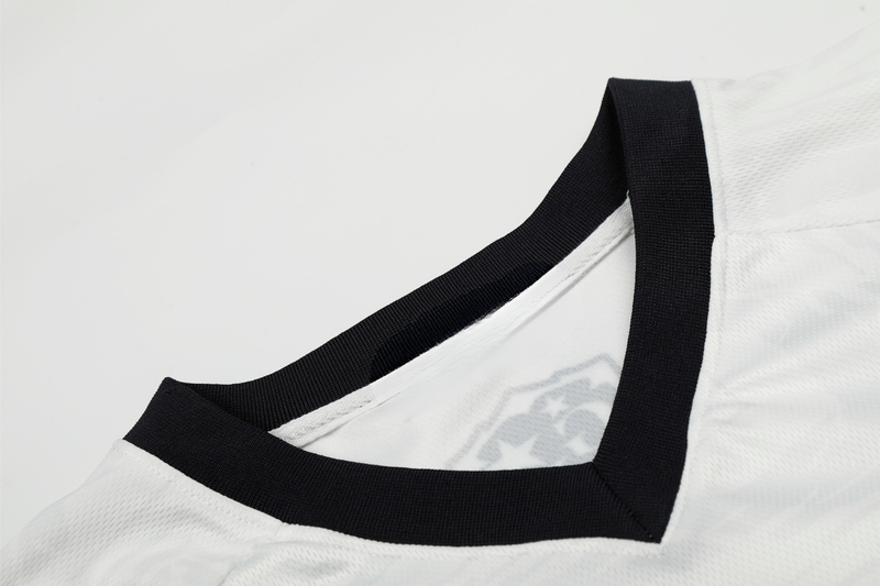 Close-up of a white mesh soccer jersey with black V-neck trim and performance fabric texture