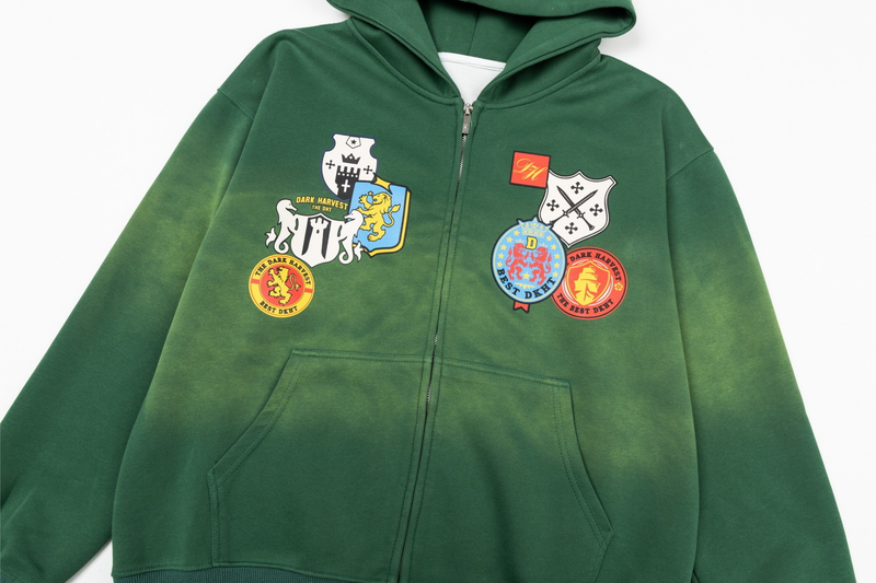 Close-up of green zip-up hoodie front with crest patches and kangaroo pocket