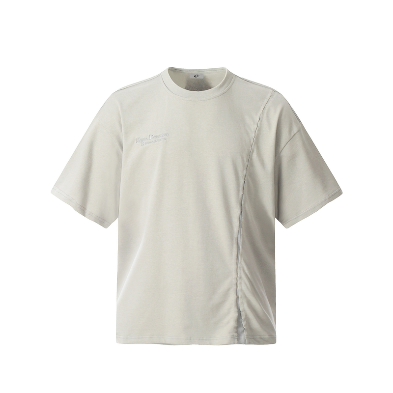 Beige asymmetric stitch tee with short sleeves, crew neck, and subtle chest embroidery on a clean white background