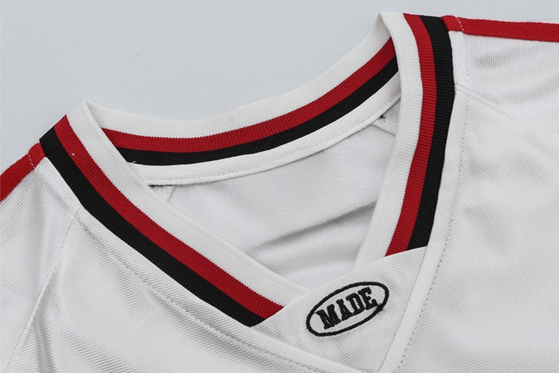White oversized football jersey with red and black striped V-neck trim and small MADE patch detail