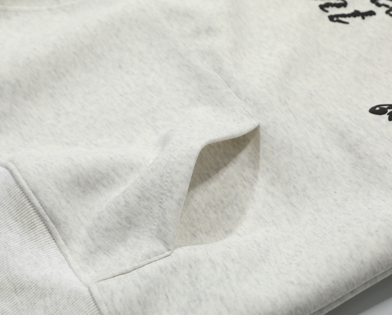 Close-up of heather gray fleece hoodie pocket and embroidered graphic detail
