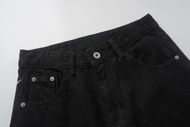 Close-up of black jeans front waistband with metal button, belt loops, and front pocket
