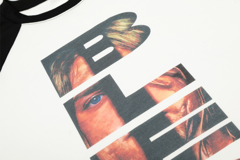 Close-up of front graphic print showing partial portrait letters on a white tee