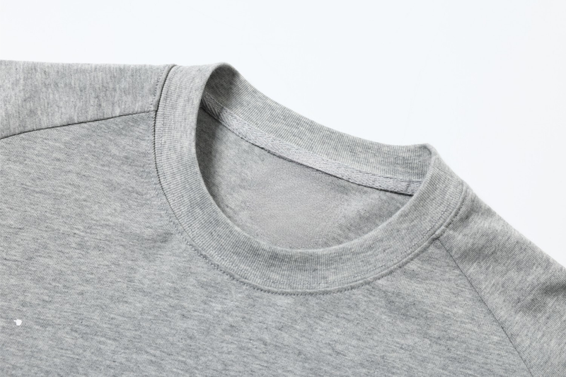 Close-up of light gray crewneck collar and shoulder seam on layered long sleeve tee