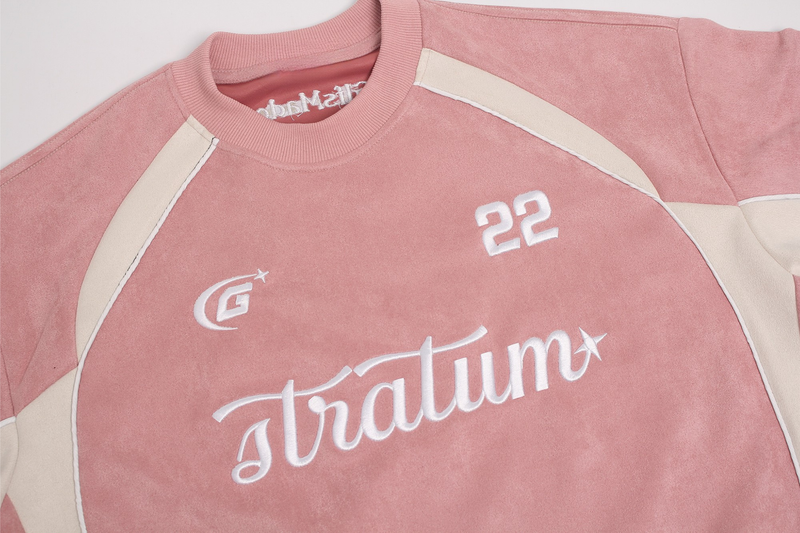 Pink suede athletic streetwear T-shirt with cream panel accents, ribbed collar, and bold white Stratum graphic on chest