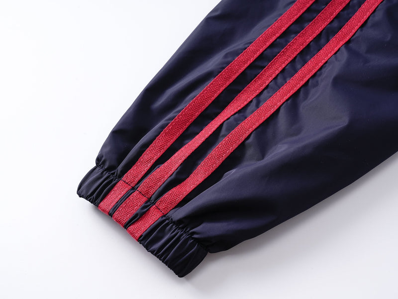 Close-up of navy sleeve with three red side stripes and elastic cuff