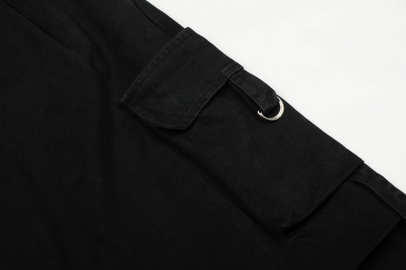 Close-up of black cargo pant leg pocket with flap and metal ring detail