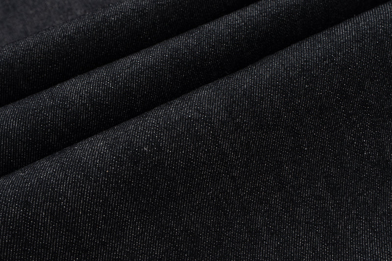 Close-up of dark denim fabric with diagonal folds and texture