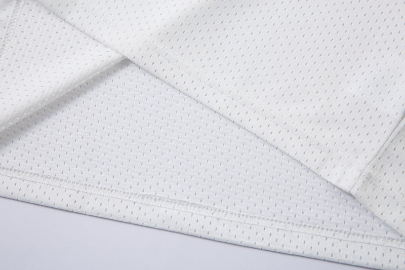 Close-up of white breathable mesh polo shirt fabric with subtle perforated texture and stitched hem detailing