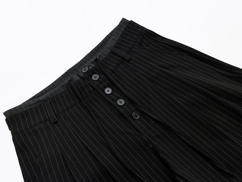 Diagonal close-up of black pinstripe shorts showing front button closure and waistband