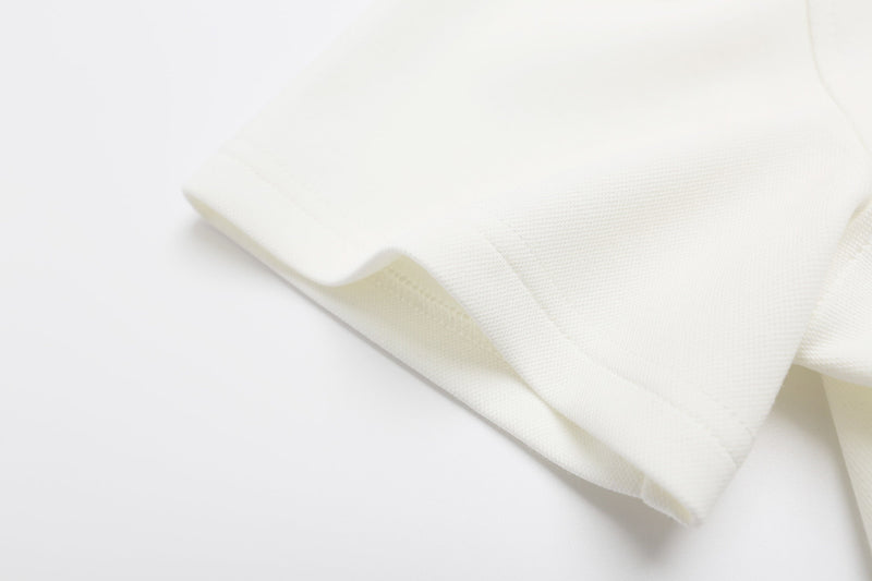 Close-up of a white polo shirt sleeve with textured fabric and neatly stitched hem on a clean background