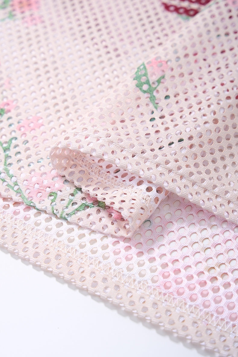Close-up of pastel pink floral mesh jersey fabric with perforated texture and folded hem details