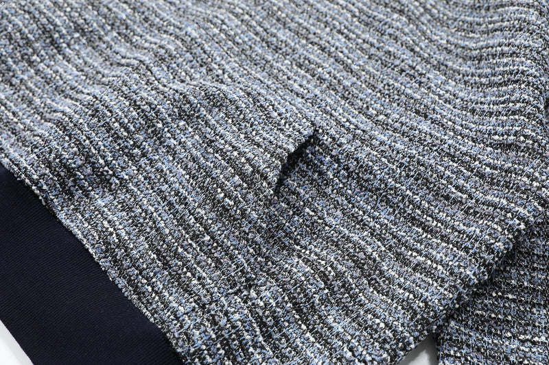 Close-up of gray and black boucle knit fabric with a small fold in the sleeve