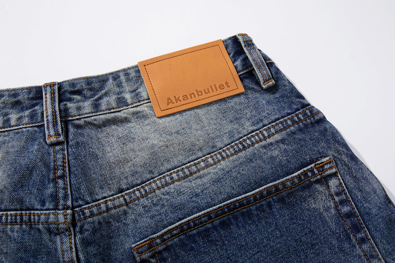 Waistband close-up showing tan leather brand patch on faded blue denim