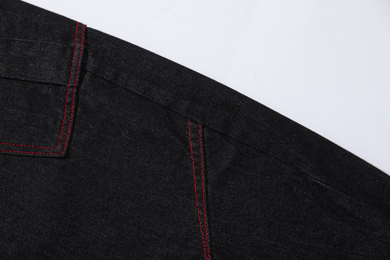Close-up of black denim panel seam with red topstitching