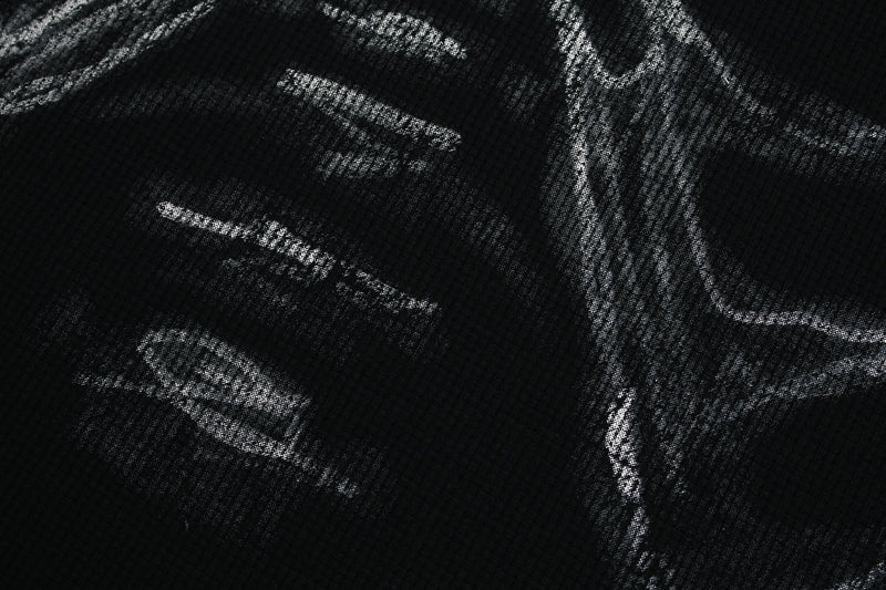 Close-up of a black graphic tee with distressed silver ribcage and heart print, bold edgy streetwear design