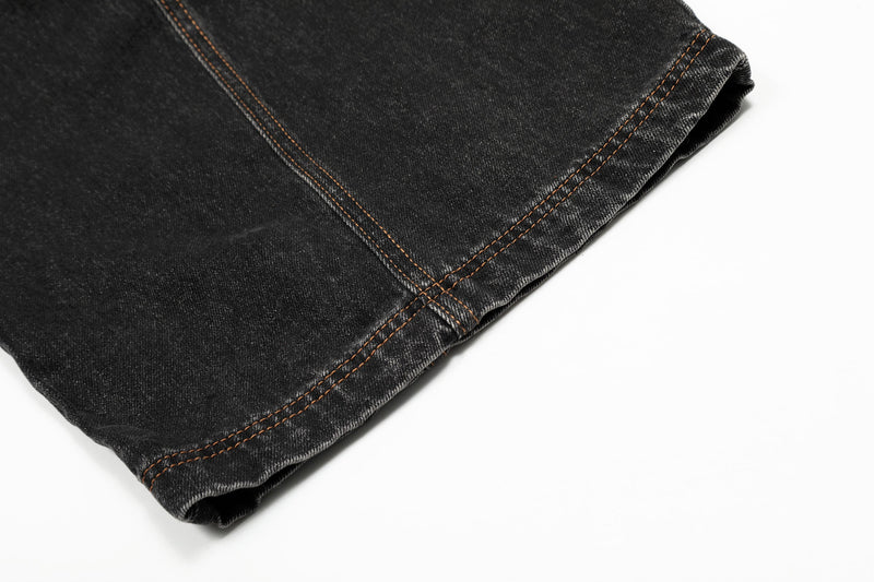 Close-up of black denim hem with orange topstitching